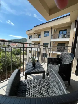 Namješten balkon sa garniturom za sjedenje i pogledom na okolne zgrade i brdo. - image 9
