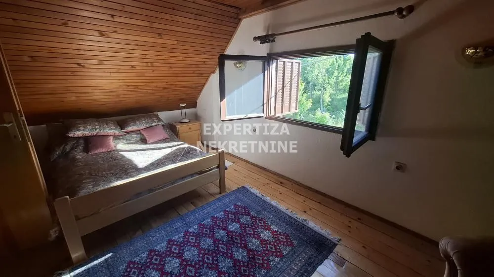 Attic bedroom with wooden ceiling and an open window.