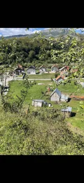 Pogled na kuće i prostrane zelene livade okružene šumom i planinama. - image 7