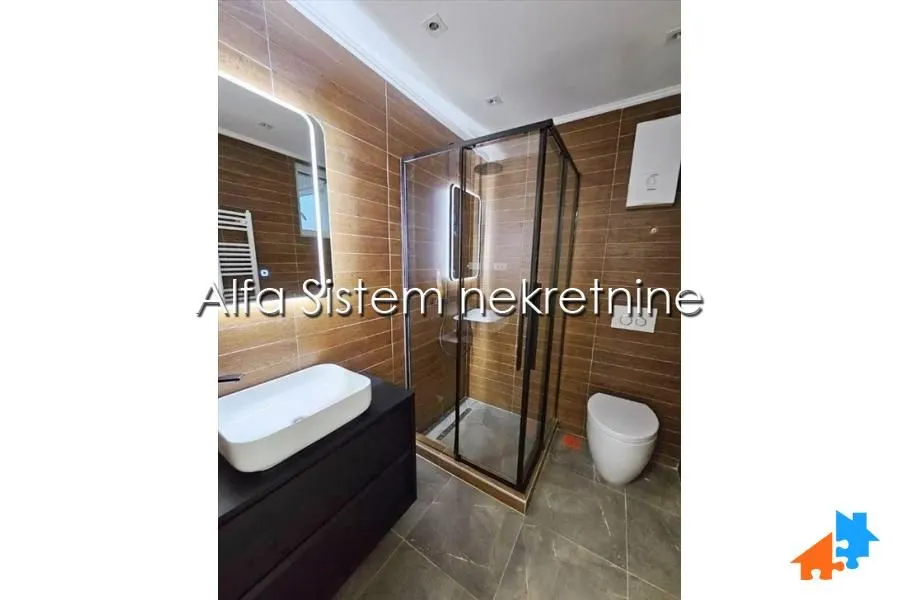 Bathroom with a walk-in shower, washbasin, and toilet, finished with ceramic tiles.