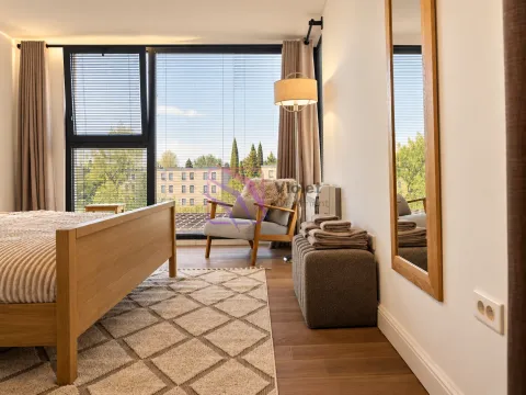 Modern bedroom with a double bed, armchair, and a large window. - image 5