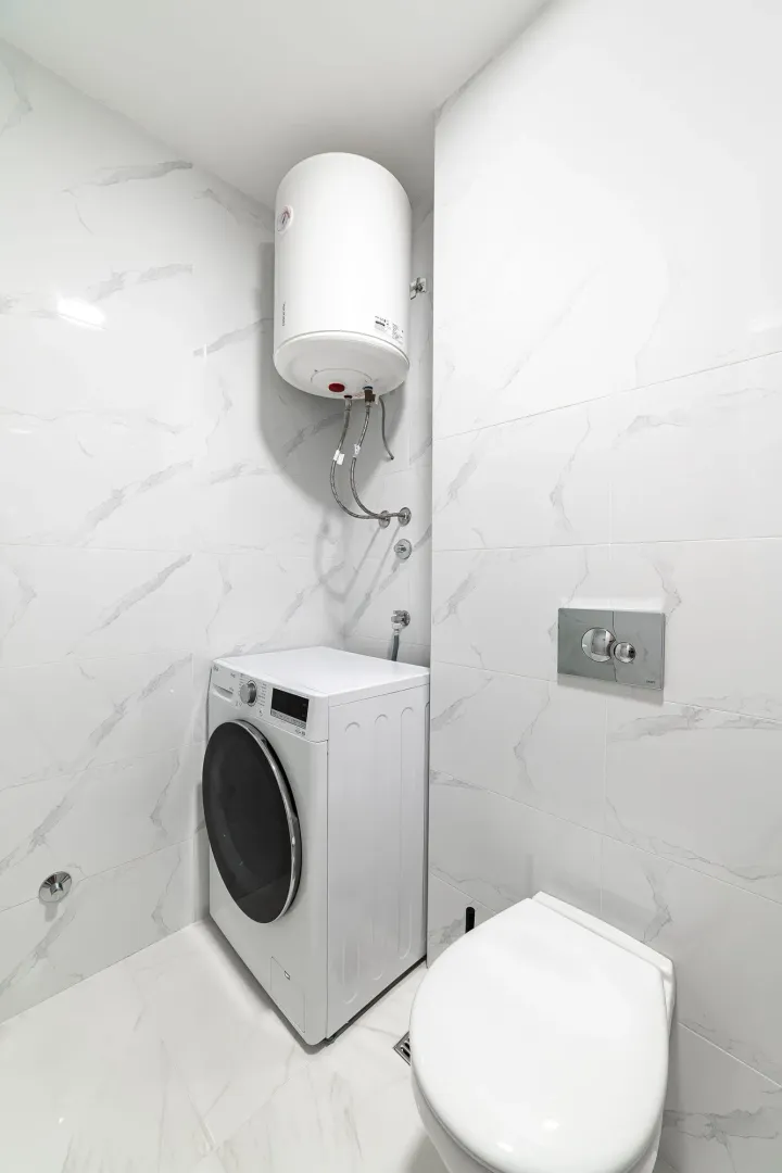 Moderno opremljeno kupatilo sa veš mašinom, bojlerom i sanitarijama.