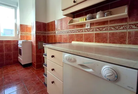 A kitchen with red wall tiles and white appliances. - image 8