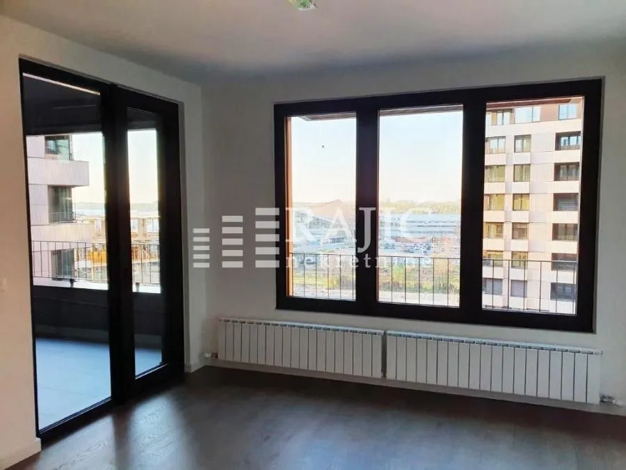Empty room with large windows and a view of surrounding buildings.
