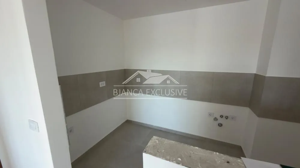 Prazan prostor za kuhinju sa zidnim pločicama i instalacijama.