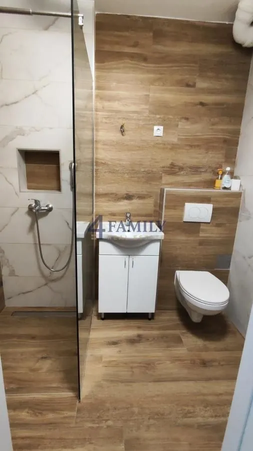 Moderno opremljeno kupatilo sa tuš kabinom i drvenim pločicama.