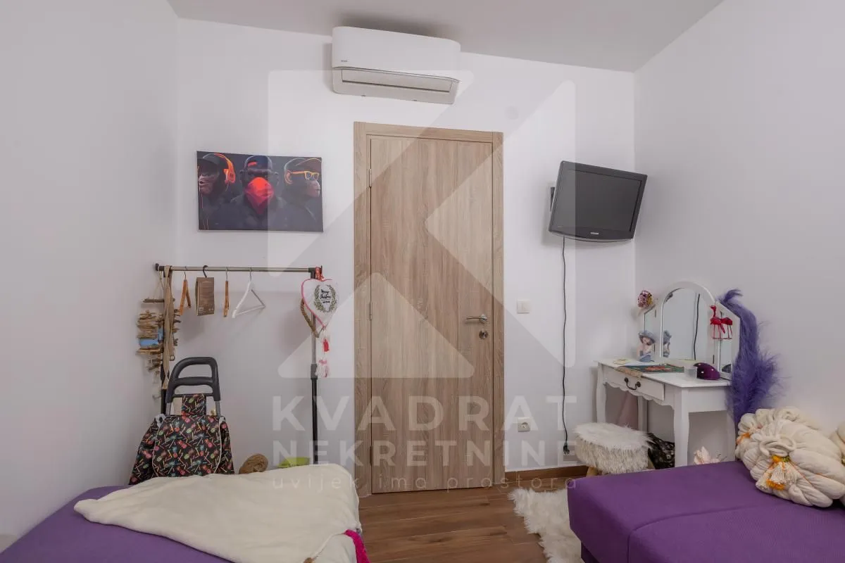 Dječija soba sa krevetom, klima uređajem i drvenim vratima.