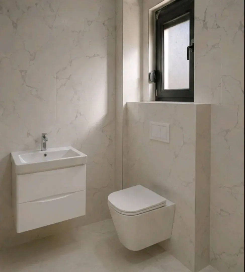 Moderne kupatilo sa mermernim pločicama, umivaonikom i wc šoljom.