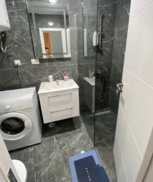 Savremeno opremljeno kupatilo sa tuš kabinom, umivaonikom i veš mašinom. - image 5