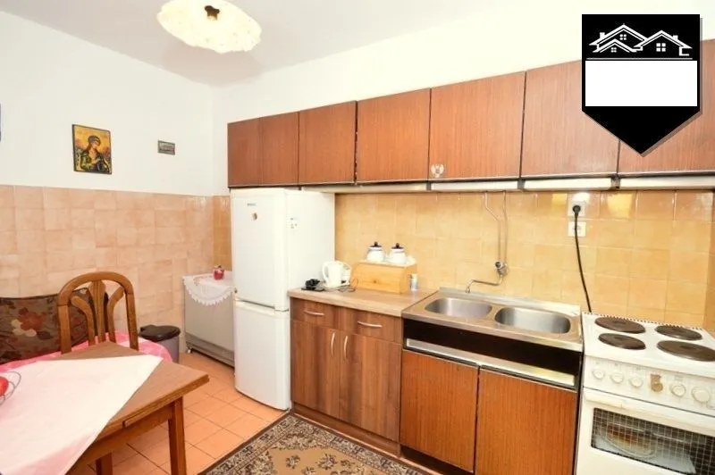 Older kitchen with wooden cabinets, a sink, and an electric stove.