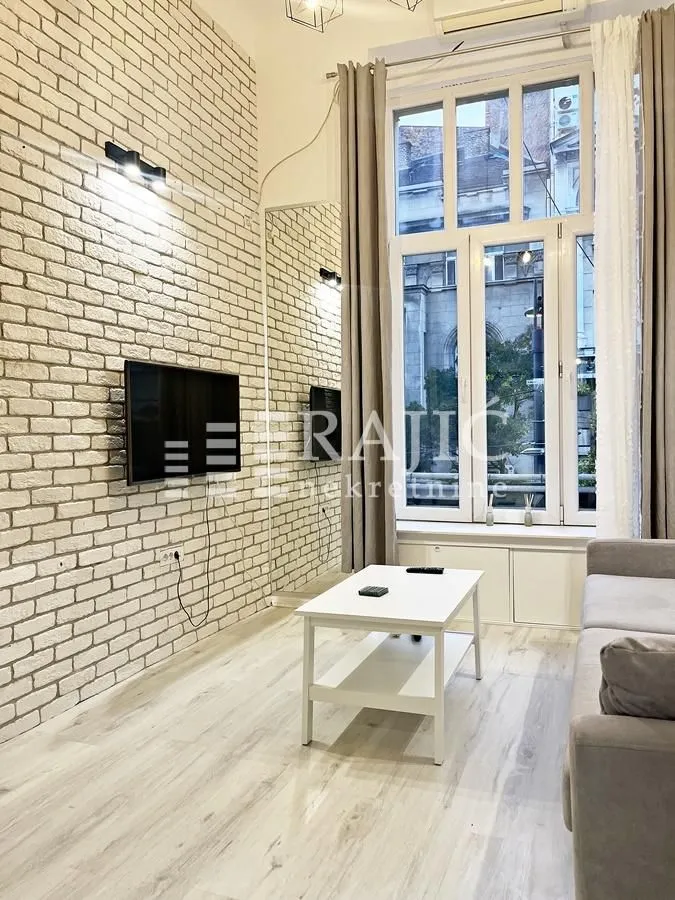 Living room with a brick wall, TV, and large window.