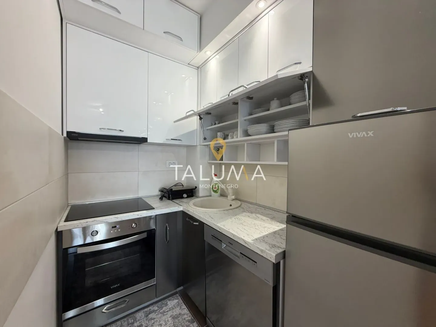 Compact white kitchen equipped with appliances.