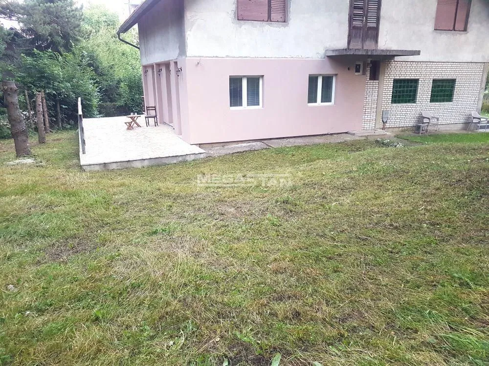 Pogled na dvorište i spoljašnjost kuće sa travnjakom.