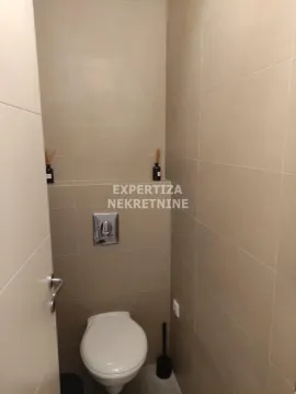 Small bathroom with a toilet and beige tiles. - image 5