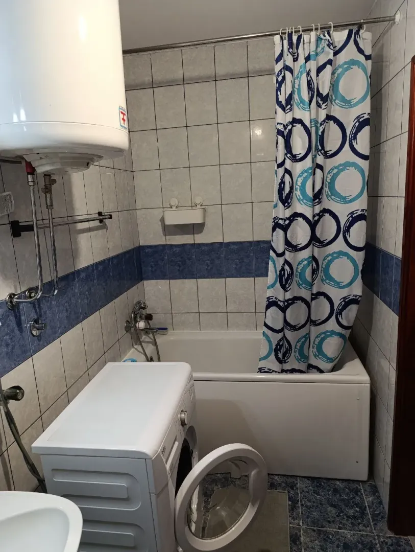 Smaller bathroom with a bathtub, water heater, and washing machine.