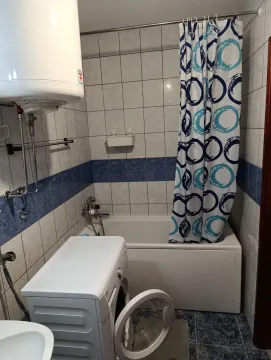 Smaller bathroom with a bathtub, water heater, and washing machine. - image 10