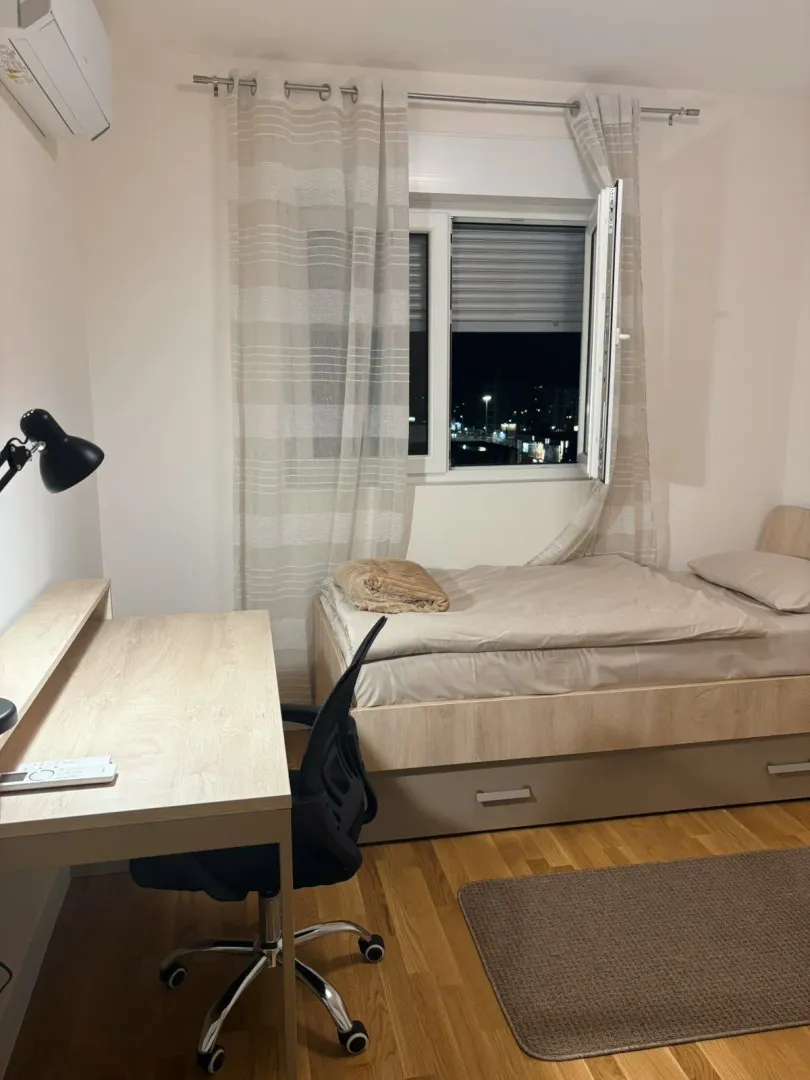 Small bedroom with a bed, desk, and window.