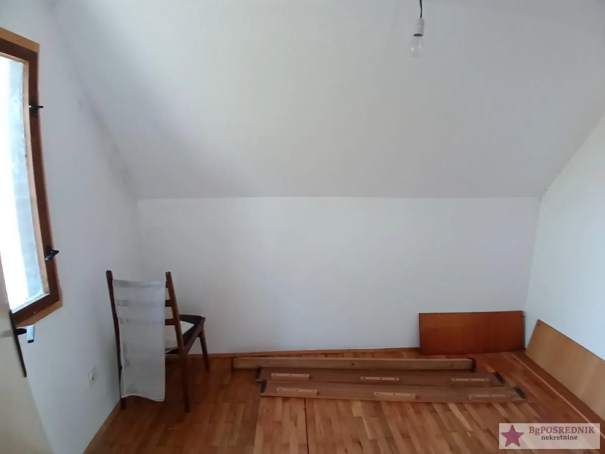 Prazna potkrovna prostorija sa drvenim podom i stolicom.