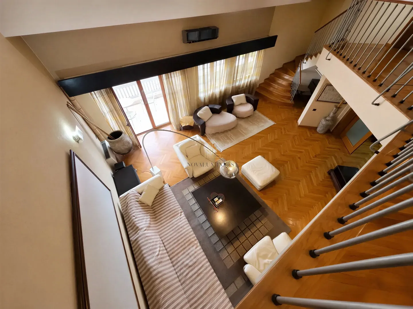 High-angle view of a spacious living room with seating area and stairs.