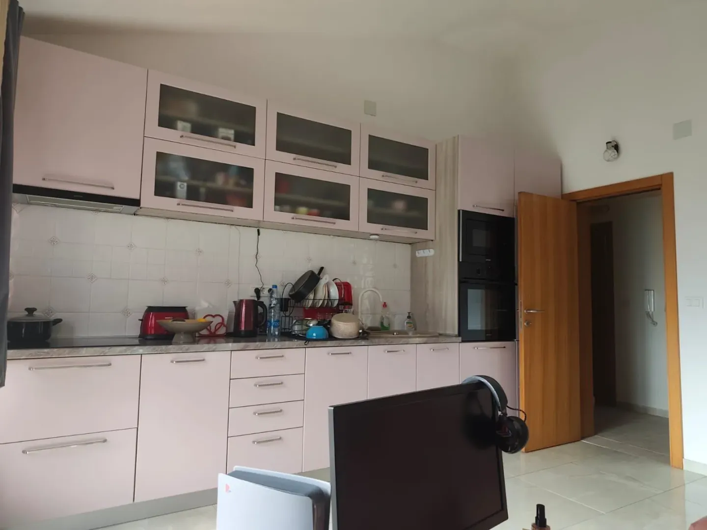 Moderna kuhinja sa roze elementima i ugradnim uređajima.