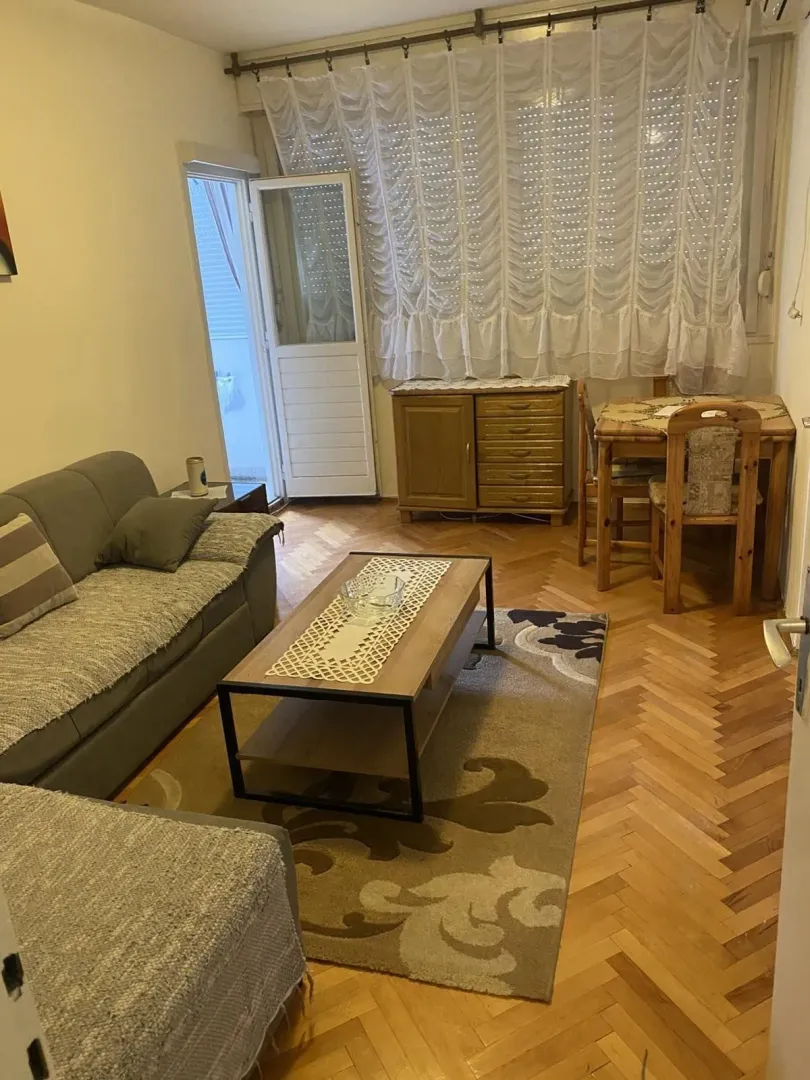 Dnevna soba sa garniturom za sjedenje i trpezarijskim stolom.