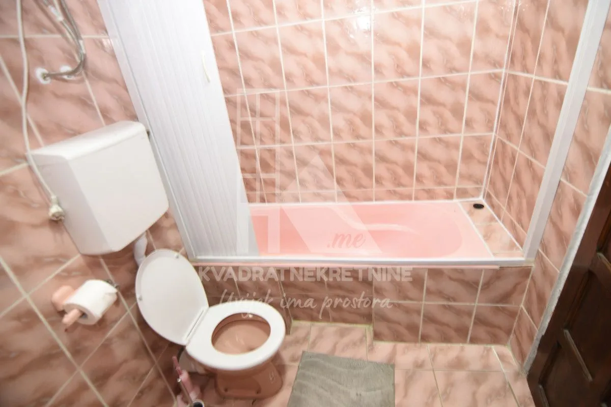 Bathroom lined with pink tiles, featuring a bathtub and a toilet.