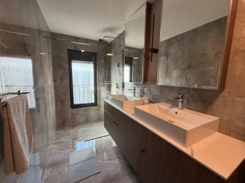 Modern bathroom with double sinks, large mirrors, and a walk-in shower. - image 15