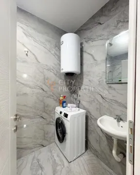 Bathroom with marble-effect tiles, washing machine, sink and water heater. - image 11