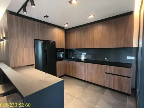 Moderna kuhinja sa drvenim elementima, crnim radnim površinama i ugrađenim aparatima. - image 5