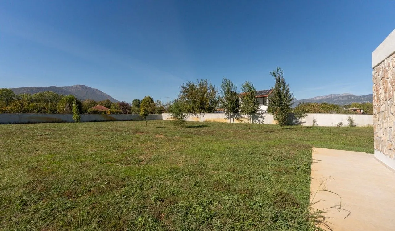 View of the spacious grassy yard and surrounding landscape with mountains.