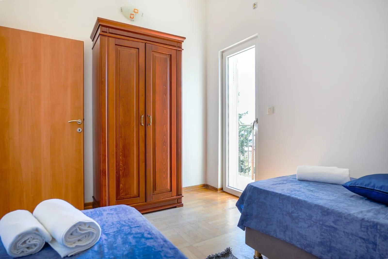 Spavaća soba sa dva kreveta i drvenim garderoberom.