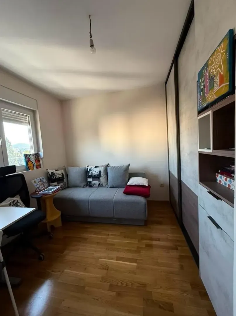 Small bedroom with a sofa, wardrobe, and desk.