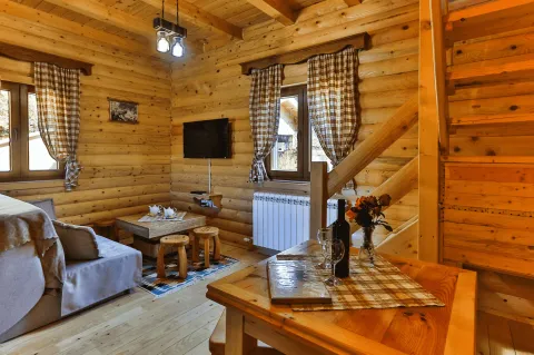 Dnevna soba u drvenoj vikendici sa garniturom, televizorom i trpezarijskim stolom. - image 10