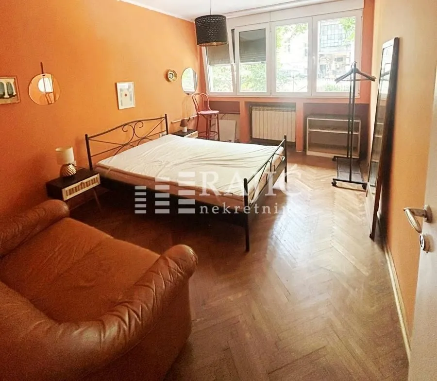 Bedroom with a double bed, sofa, and orange walls.