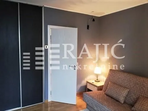 Furnished bedroom with a sofa bed and built-in wardrobe.