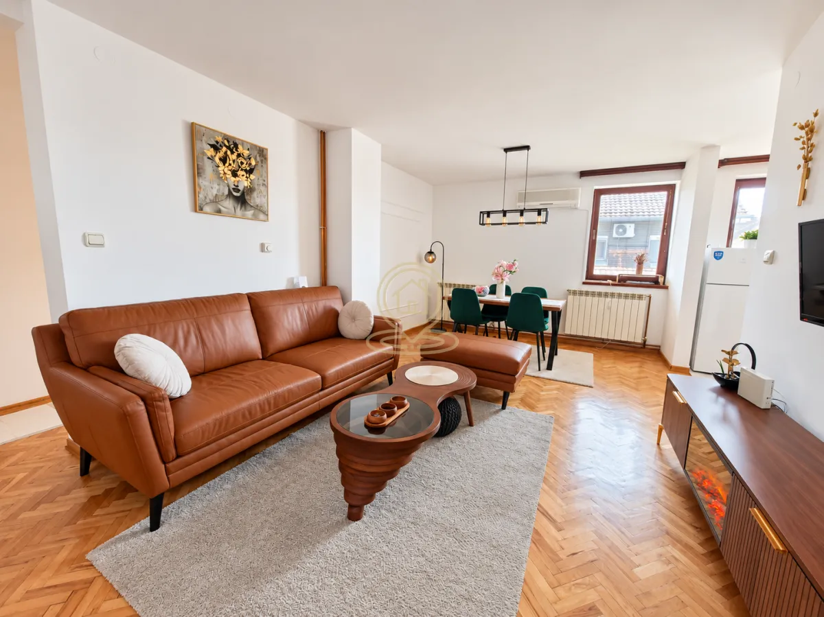 Spacious living room with a leather sofa and a dining area in the background.