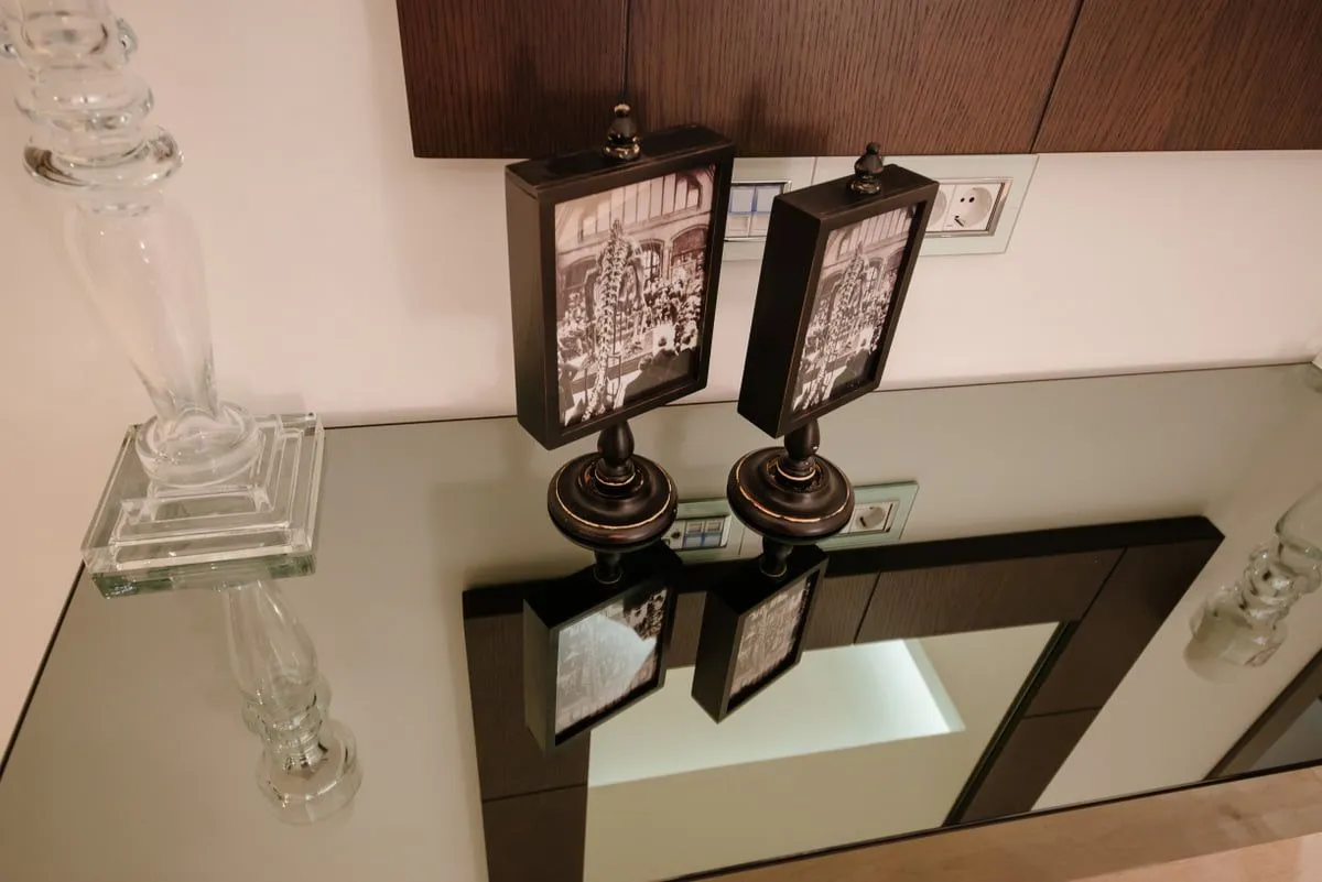Ukrasni detalji i ramovi za slike na konzolnom stolu sa ogledalom.
