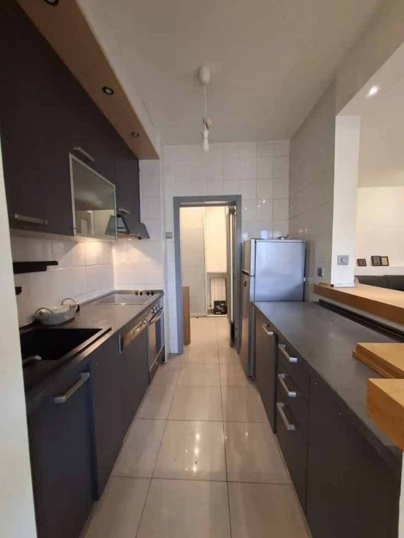 Narrow kitchen with dark cabinetry and white wall tiles.