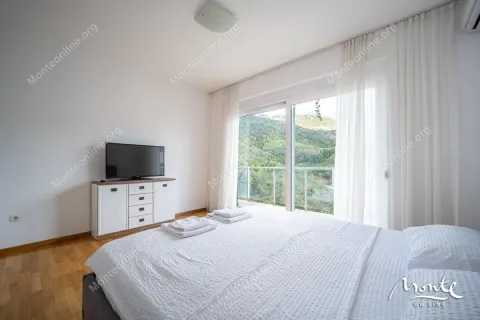 Bedroom with a double bed, chest of drawers, TV, and access to a terrace with a forest view. - image 23