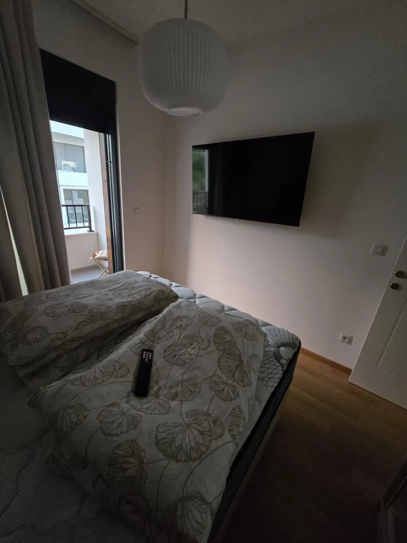 Bedroom with a bed, wall-mounted television, and access to the terrace.