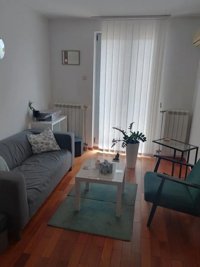 Manja dnevna soba sa garniturom za sedenje i izlazom na terasu.