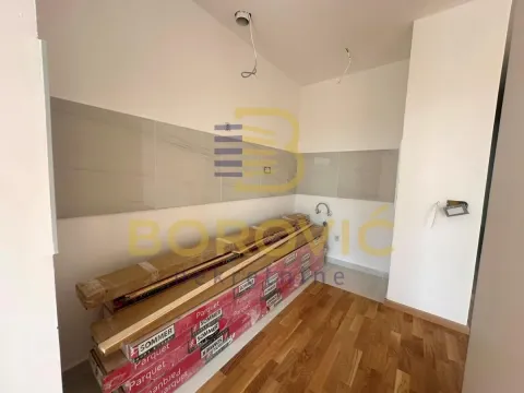 Nedovršena kuhinja sa pločicama i parketom spakovanim na podu. - image 4