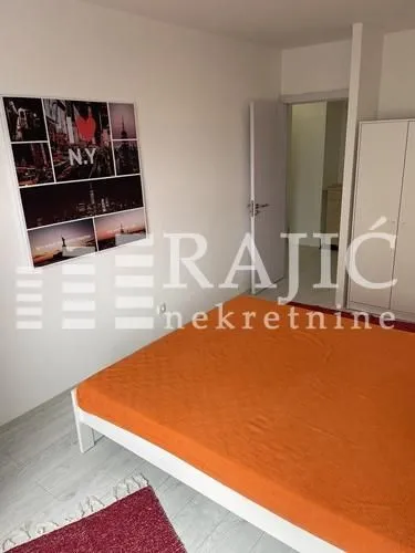 Furnished bedroom with a double bed and a wardrobe.