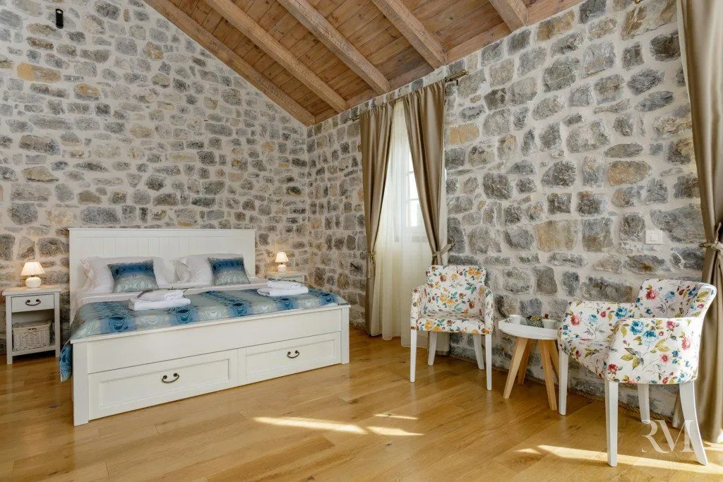 Bedroom with a double bed, wooden floor, and stone walls.