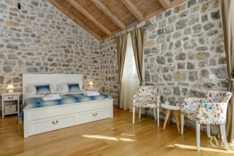 Bedroom with a double bed, wooden floor, and stone walls. - image 14