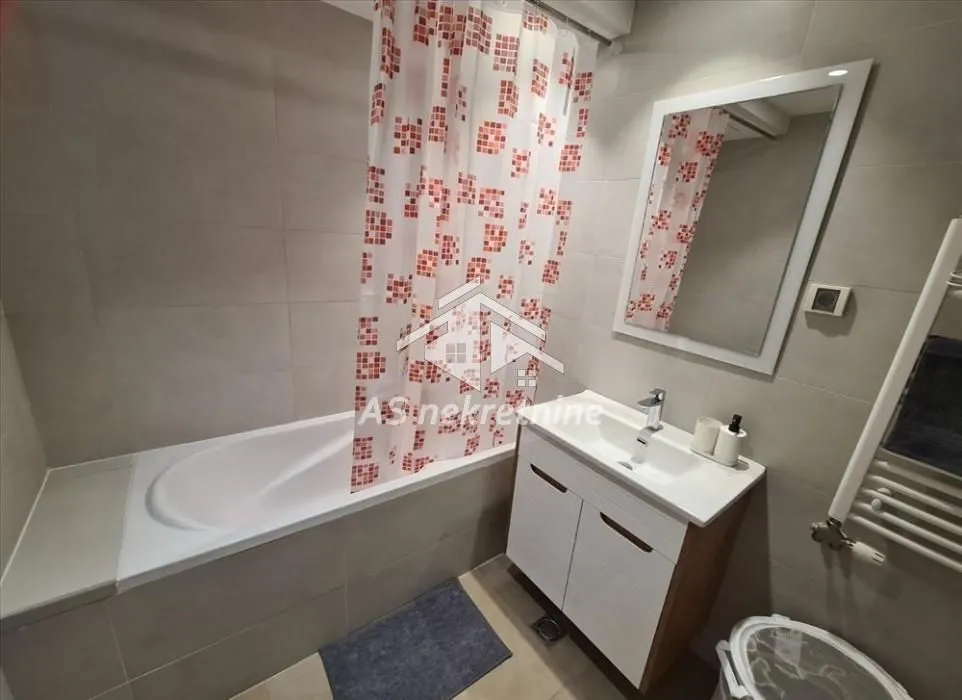 Modern bathroom with a bathtub, washbasin, and mirror.