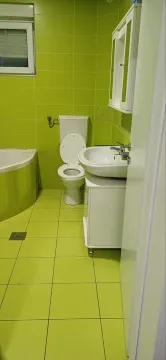 Small bathroom with green tiles, washbasin, and toilet. - image 10