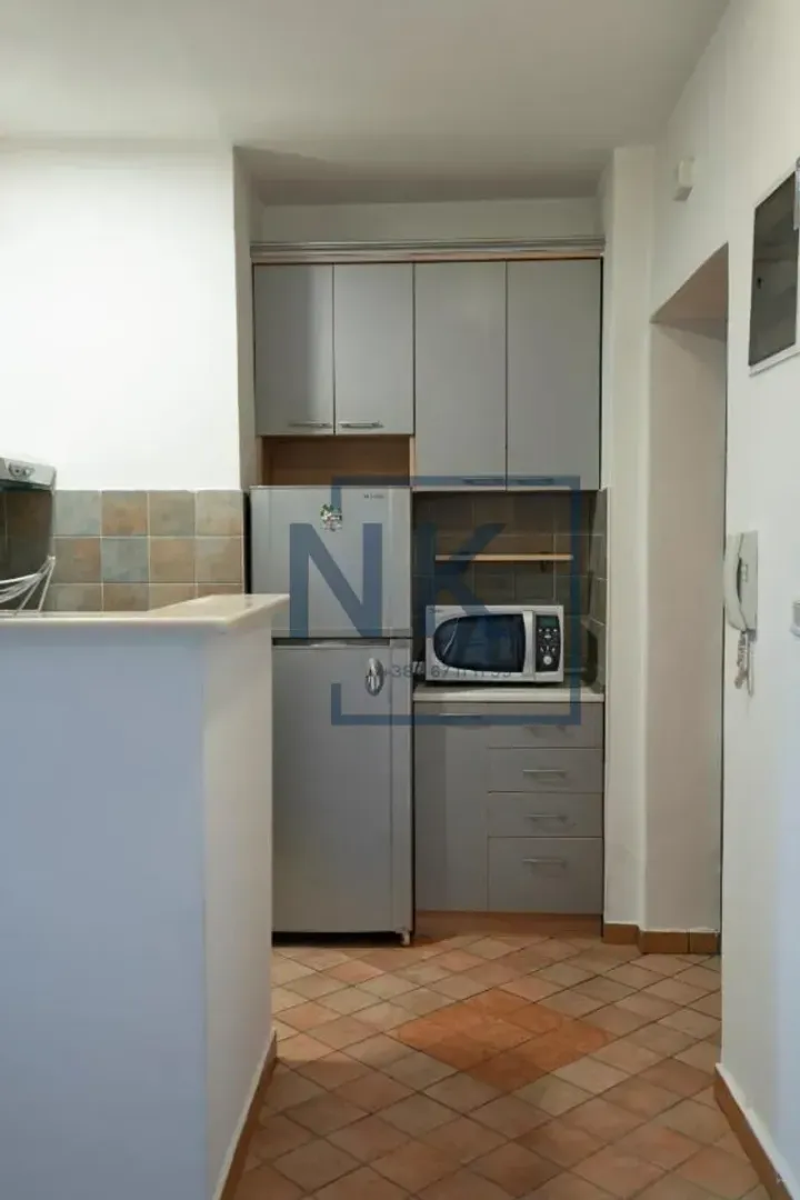 Small kitchen with grey cabinets and a refrigerator.