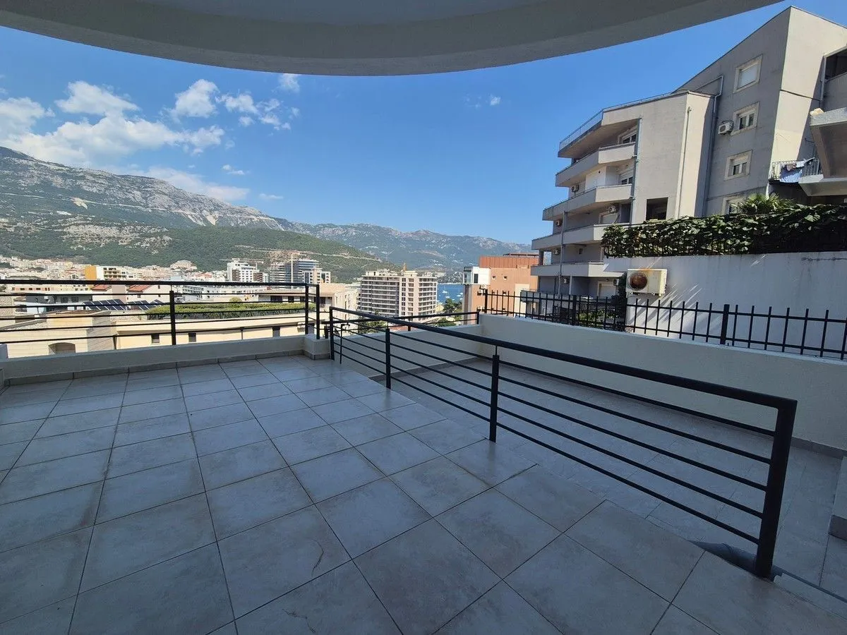 Spacious tiled terrace with a view of the city, surrounding buildings and mountains.