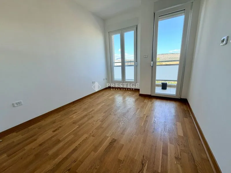 Prazna soba sa drvenim podom i izlazom na terasu.